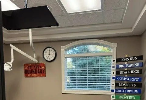 A flat-screen TV mounted on the ceiling above the chair in a Times Square Dental care room.