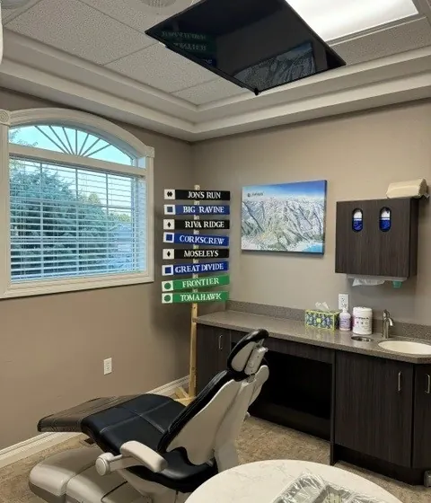A care room at Times Square Dental with its ceiling TV and a painted trail map on the wall.